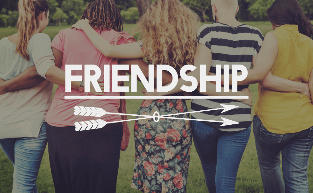 Five people stand arm-in-arm in a grassy area, embodying the essence of Friendship, much like the warmth and wisdom found in Bible verses about friendship.